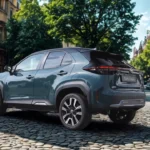 2025 Toyota Yaris Cross achter drie-kwart hoek op boomrijke straat met achterklep, achterruit en compacte crossover-ontwerp