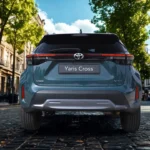 Direct achteraanzicht van 2025 Toyota Yaris Cross met volledige achterlichtspan, geïntegreerde achterspoiler en achterklep-ontwerp op kasseistraat