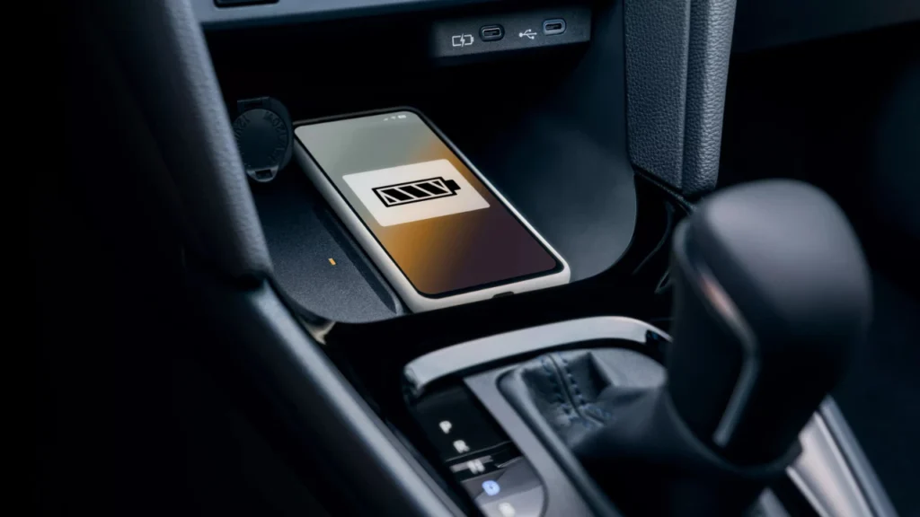 2025 Toyota Yaris Cross draadloze oplaadpad in middenconsole met smartphone die oplaadstatus en batterij-indicator toont
