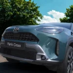 Close-up vooraanzicht van 2025 Toyota Yaris Cross met gedetailleerd grille-patroon, LED-koplampenclusters en Toyota-logo op blauwgroene motorkap