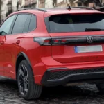 Achter driekwart zicht van rode 2025 Volkswagen Tiguan met SUV-proporties, LED-achterlichten en hedendaagse achter design elementen