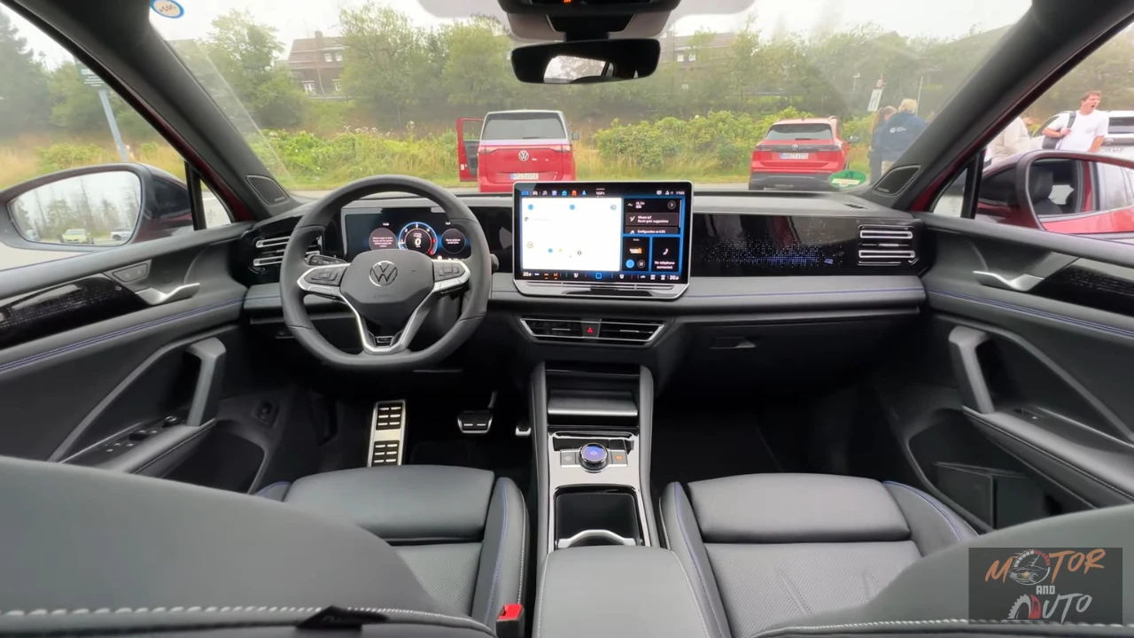 Interieurzicht van 2025 Volkswagen Tiguan met dashboard, groot touchscreen display, stuurwiel en zwarte stoelen met blauwe siernaad