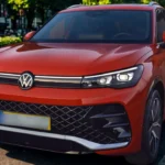 Voorkant driekwart zicht van rode 2025 Volkswagen Tiguan met modern SUV design, LED-koplampen, mesh grille en sportieve voorbumper