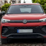Directe voorkant zicht van rode 2025 Volkswagen Tiguan met volledige voorgevel, LED-koplampen, VW-badge en mesh grille patroon
