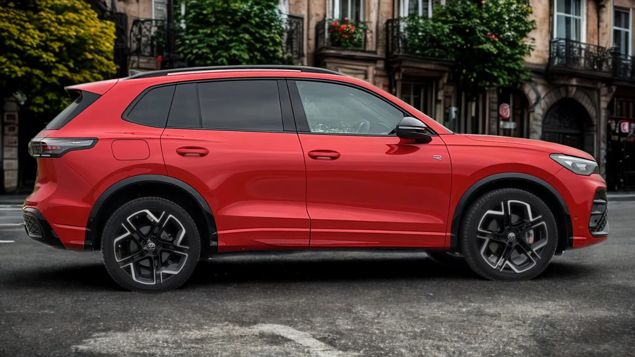 Zijaanzicht van rode 2025 Volkswagen Tiguan geparkeerd op kinderkopjes met compleet SUV-profiel, lichtmetalen wielen en stedelijke achtergrond