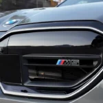 Close-up detail van 2025 BMW M5 zwarte niergrille met M5 prestatie-badge met blauwe, rode en witte M-kleuren