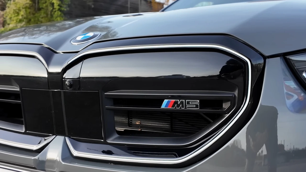 Close-up detail van 2025 BMW M5 zwarte niergrille met M5 prestatie-badge met blauwe, rode en witte M-kleuren