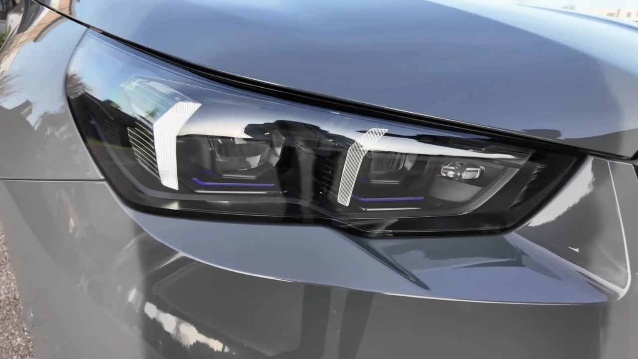 Gedetailleerd aanzicht van 2025 BMW M5 LED-koplamp assemblage met blauwe accentstrepen, meerdere lichtelementen en modern design