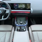 Interieur vooraanzicht van de 2025 BMW X3 M50 met curved display, M Sport stuurwiel en luxe stoelen