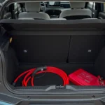 Open achter bagageruimte van 2025 Citroën ë-C3 elektrische auto met kofferbakruimte, rode laadkabels, noodpakket tas en praktische opbergvakken