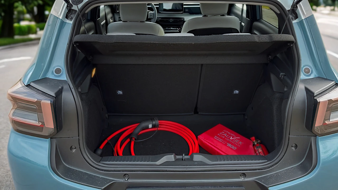 Open achter bagageruimte van 2025 Citroën ë-C3 elektrische auto met kofferbakruimte, rode laadkabels, noodpakket tas en praktische opbergvakken