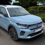 Lichtblauwe 2025 Citroën ë-C3 elektrische auto geparkeerd op asfalt met front- en zijprofiel, moderne LED-koplampen, zwarte wielkasten en kenmerkende lichtmetalen velgen