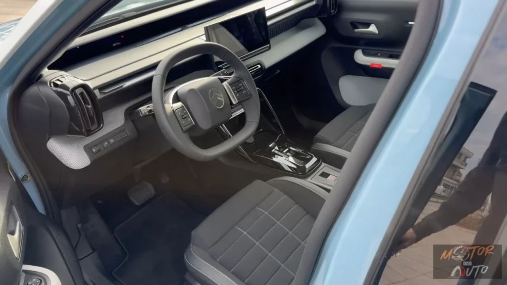 Voor interieurbeeld van 2025 Citroën ë-C3 elektrische auto met grijs dashboard, Citroën stuurwiel, gewatteerde stoelbekleding en moderne interieurdesign-elementen