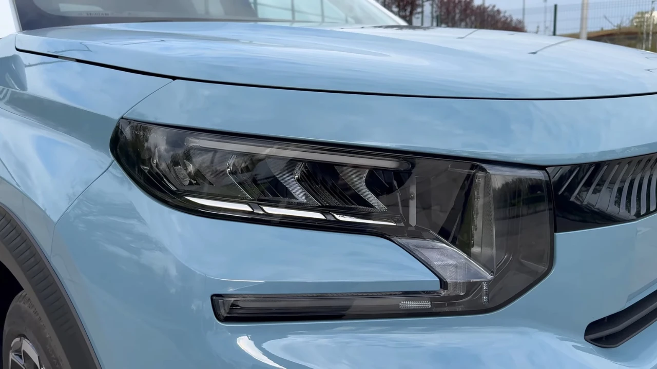 Gedetailleerd beeld van 2025 Citroën ë-C3 LED-koplamp met moderne lichtsignatuur, dagrijverlichting en strak design geïntegreerd in het lichtblauwe carrosseriepaneel