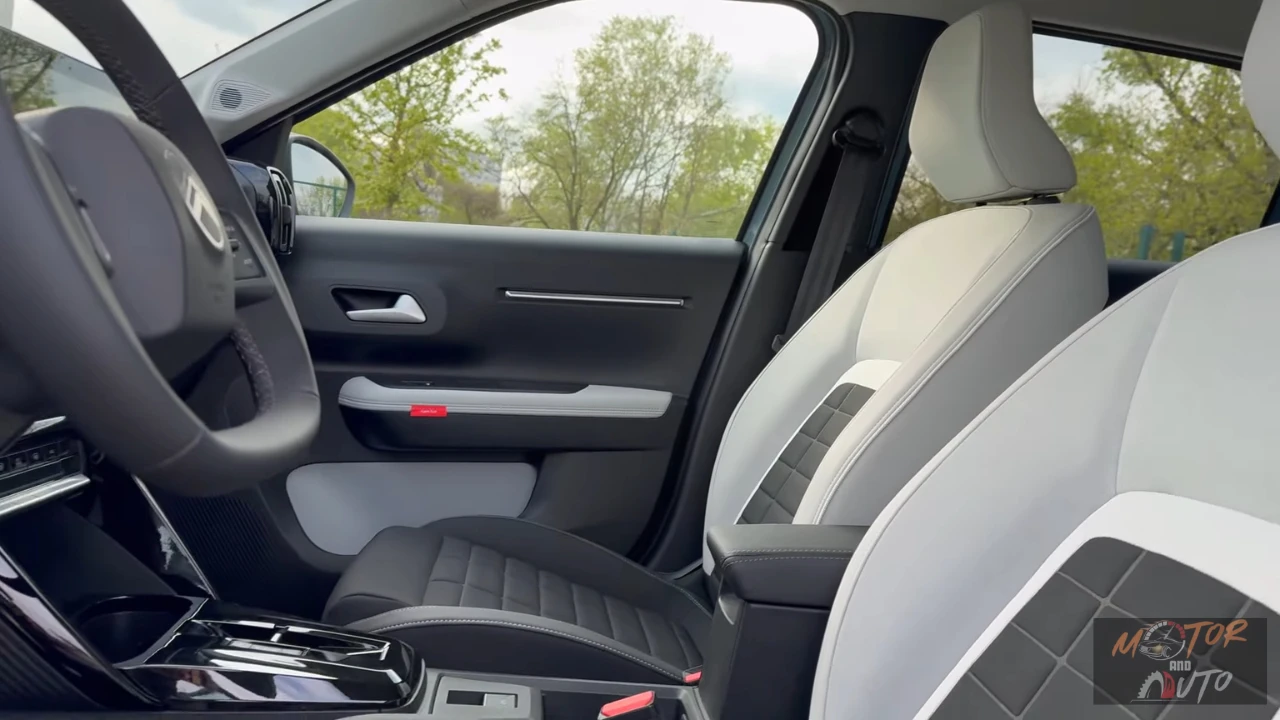 Close-up van 2025 Citroën ë-C3 voorstoelen met gewatteerde stoffen bekleding in grijze en zwarte kleuren met wit contrastgaren en modern stoeldesign