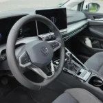 Bestuurderszijde van VW Golf interieur met focus op stuurwielbediening en instrumentendisplays