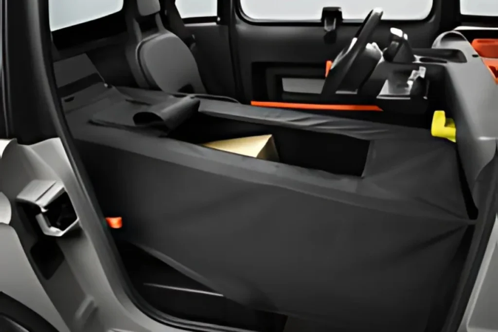Interieur close-up van Citroën Ami Cargo variant met zwart modulair laadplatform met verborgen opbergruimte en oranje accentafwerking