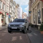 Een vooraanzicht van een zilverkleurige Dacia Duster, geparkeerd in een geplaveide straat in Amsterdam, waarbij het gedurfde ontwerp van de voorkant goed te zien is.