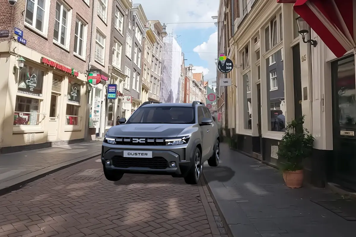 Een vooraanzicht van een zilverkleurige Dacia Duster, geparkeerd in een geplaveide straat in Amsterdam, waarbij het gedurfde ontwerp van de voorkant goed te zien is.