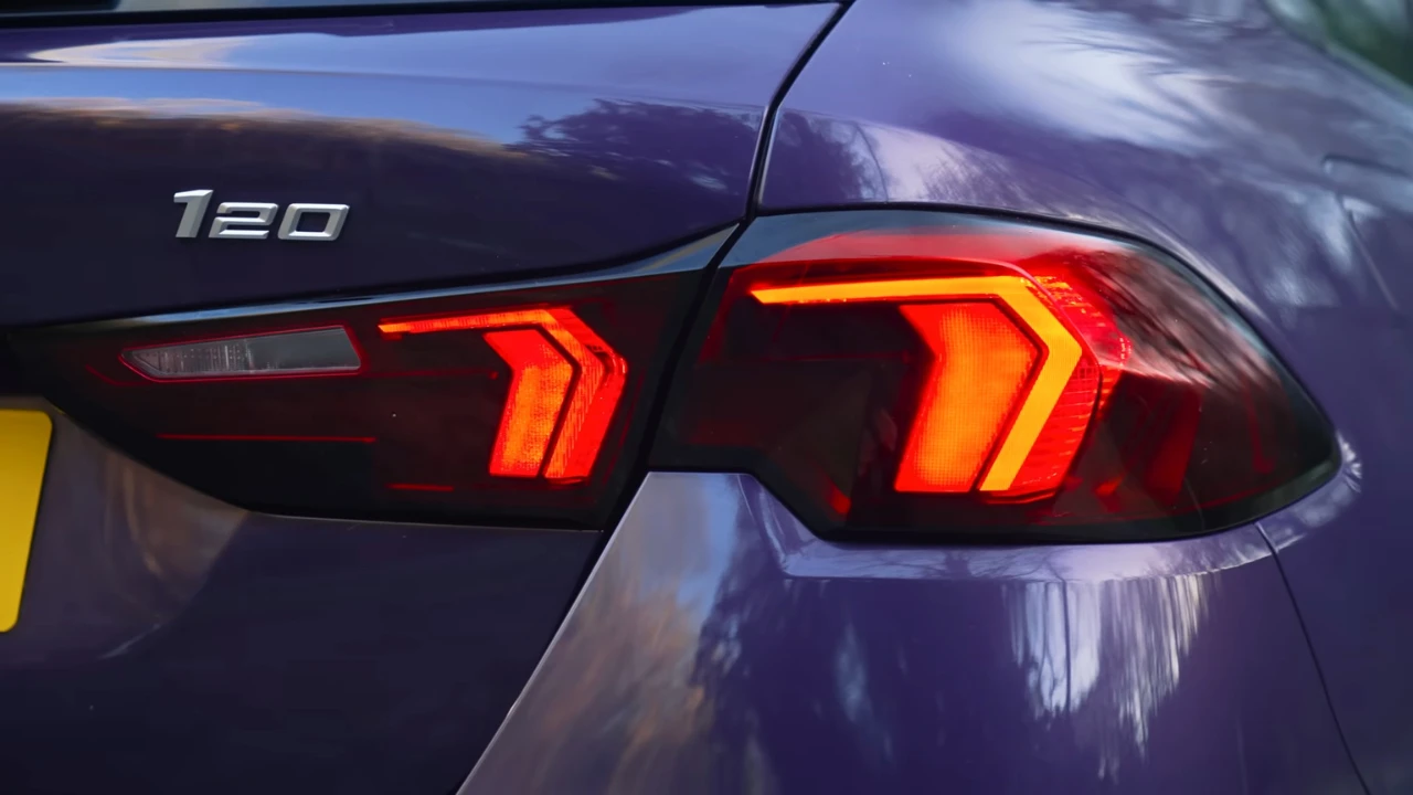 2025 BMW 1 Serie 120i achterlicht detail met modern LED-ontwerp met oranje en rode elementen, modelbadge en premium paarse metallic lakafwerking