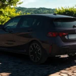 2025 BMW 1 Serie achter driekwart zicht in landschappelijke natuurlijke omgeving met heuvels en groen op de achtergrond, hatchback proporties en paarse metallic lakafwerking