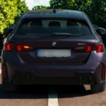 2025 BMW 1 Serie achteraanzicht met kenmerkende LED-achterlichten, 120i modelbadge, achterdiffuser en hatchback ontwerp in paarse metallic lak op stedelijke straat