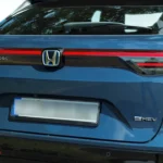 2025 Honda HR-V achter badge detail met Honda embleem, HR-V letters, e:HEV hybride badge en LED-achterlicht elementen op blauwe afwerking.