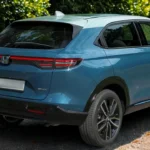 2025 Honda HR-V driekwart achterhoek in blauw met SUV-verhoudingen, stijlvolle lichtmetalen wielen, achterspoiler en eigentijdse crossover-styling.