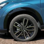 2025 Honda HR-V lichtmetalen wiel close-up met multi-spaken ontwerp, Honda middendop, band zijwand en blauw gelakt carrosseriepaneel detail.