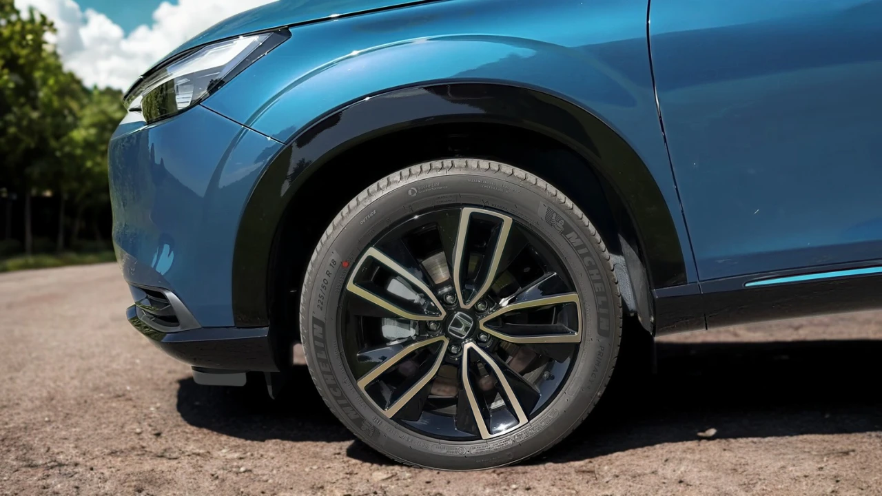 2025 Honda HR-V lichtmetalen wiel close-up met multi-spaken ontwerp, Honda middendop, band zijwand en blauw gelakt carrosseriepaneel detail.