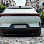 Directe achteraanzicht van witte 2025 Polestar 4 elektrische auto op kinderkopjesstraat met volle breedte LED-achterlichtbalk, minimalistisch achterontwerp en Europees kenteken