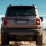 Achteraanzicht van 2025 Toyota Land Cruiser met "LAND CRUISER" embleem, rijdend in woestijn met ander voertuig volgend erachter