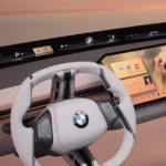 Close-up weergave van BMW's witte stuurwiel en centraal display met multimedia-interface in warme verlichtingssfeer