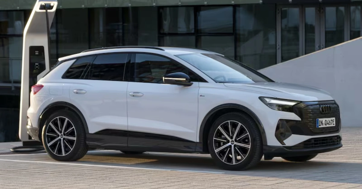 Zijprofiel van witte Audi Q4 40 e-tron geparkeerd bij een elektrisch laadstation, met zijn gestroomlijnde SUV-silhouet en kenmerkend wielontwerp