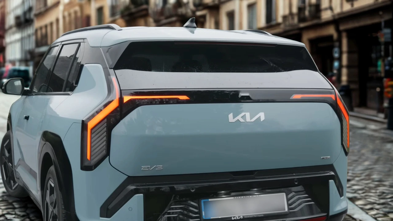 Witte 2025 Kia EV3 elektrische SUV van achteren, met oranje LED-achterlichten, KIA-logo en EV3-badge op historische Europese kasseienstraat