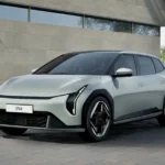 Zilveren Kia EV4 elektrisch voertuig getoond vanuit de voorkant kwartierhoek, met zijn kenmerkende Tiger Face-design, verticale koplampen en aerodynamisch profiel tegen een moderne architecturale achtergrond