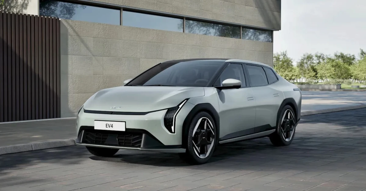 Zilveren Kia EV4 elektrisch voertuig getoond vanuit de voorkant kwartierhoek, met zijn kenmerkende Tiger Face-design, verticale koplampen en aerodynamisch profiel tegen een moderne architecturale achtergrond