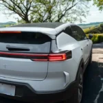 Witte 2025 Polestar 3 elektrische SUV achter-driekwart aanzicht op landelijke weg met heuvels en plattelandslandschap op de achtergrond