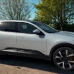 Witte 2025 Polestar 3 elektrische SUV zijprofielaanzicht in lente-omgeving met groen gras en bloeiende planten
