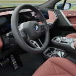 Interieur dashboard-aanzicht van de 2026 BMW iX met roze lederen bekleding en curved display