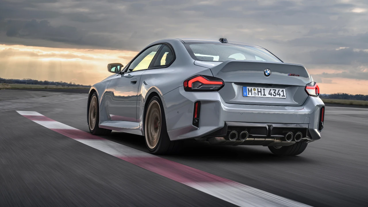 Dynamisch achter drie-kwart zicht van 2025 BMW M2 CS op circuit met koolstofvezel achterdiffuser, eendenstaart spoiler, brede achterbanden, en agressief aerodynamisch pakket in beweging