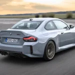 Achter drie-kwart zicht van 2025 BMW M2 CS met geïntegreerde eendenstaart spoiler, koolstofvezel achterdiffuser, viervoudige uitlaatpijpen, en M2 CS badge met rode omlijning