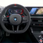 Bestuurders perspectief van 2025 BMW M2 CS cockpit met M stuurwiel met schakelpeddels, digitaal instrumentencluster, koolstofvezel trim, en M-specifieke bedieningsknoppen
