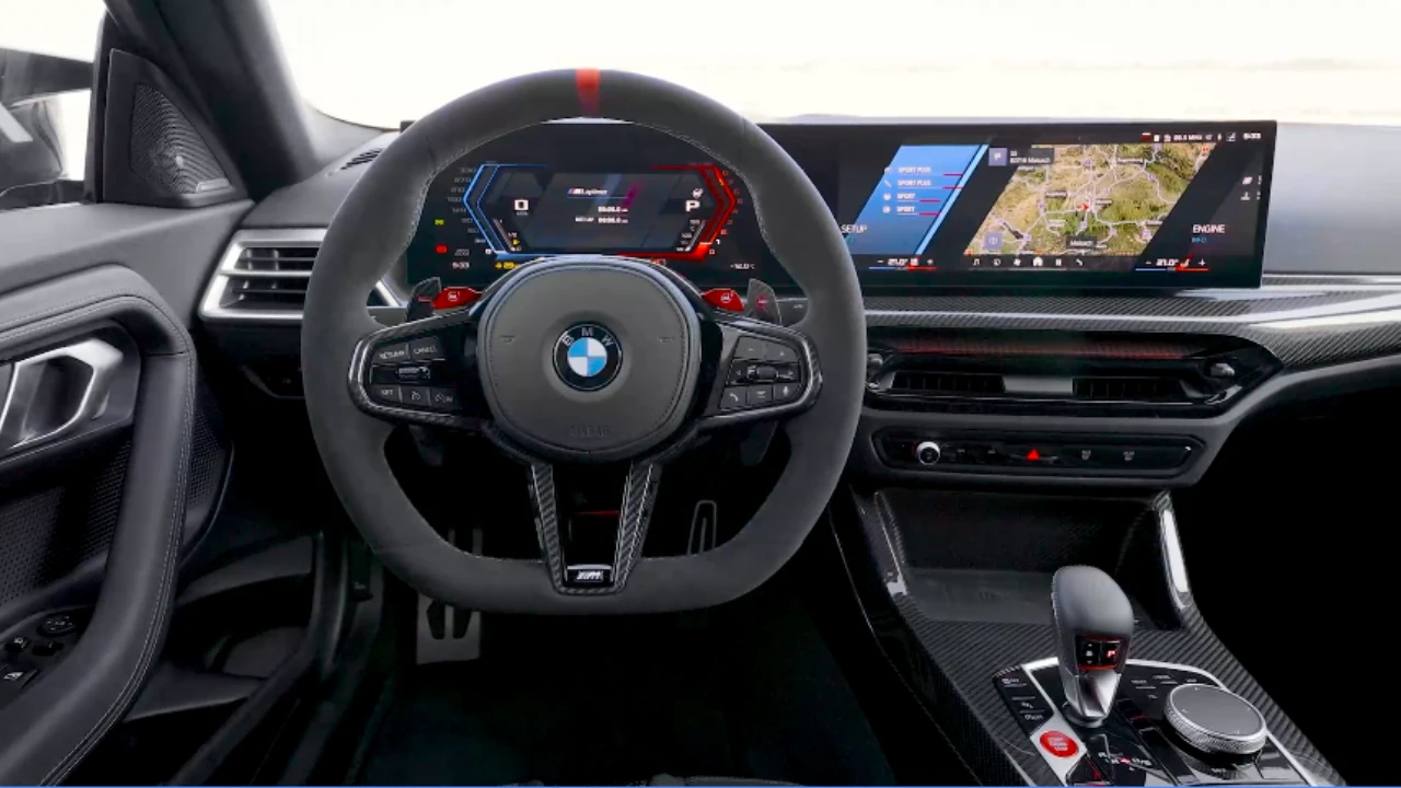 Bestuurders perspectief van 2025 BMW M2 CS cockpit met M stuurwiel met schakelpeddels, digitaal instrumentencluster, koolstofvezel trim, en M-specifieke bedieningsknoppen