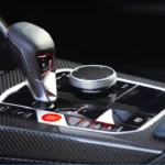 Middenconsole van 2025 BMW M2 CS met 8-traps M Steptronic schakelaar, koolstofvezel trim, M Drive knoppen, iDrive controller, en rode CS branding accenten