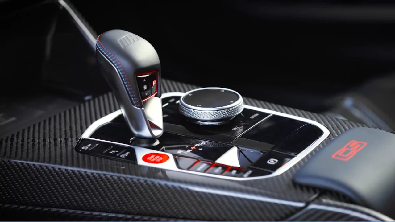 Middenconsole van 2025 BMW M2 CS met 8-traps M Steptronic schakelaar, koolstofvezel trim, M Drive knoppen, iDrive controller, en rode CS branding accenten