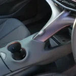 Close-up van de 2025 CUPRA Tavascan's onderscheidende centrale ruggengraat ontwerp met bekerhouders, opbergvakken en de kenmerkende getextureerde afwerking die de unieke cabine-ambiance creëert.
