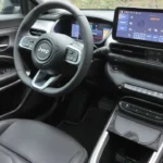 Interieur zicht toont 2025 Jeep Avenger infotainment touchscreen met moderne interface, fysieke klimaatregeling en stuurwiel
