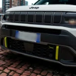 Gedetailleerd vooraanzicht van 2025 Jeep Avenger toont iconische zeven-slot grille, LED koplampen en gele accentdetails op voorbumper
