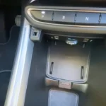 Middenconsole van de 2025 Jeep Avenger met draadloze oplaadpad, meerdere opbergvakken en USB-connectiviteitspoorten voor apparaten.